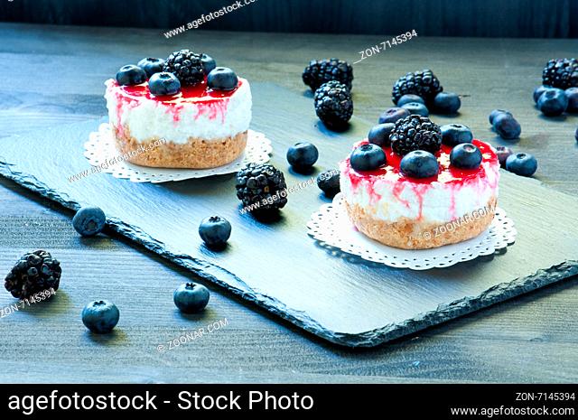 delicious strawberry cheese cake on a black plate with fresh blueberries in the background