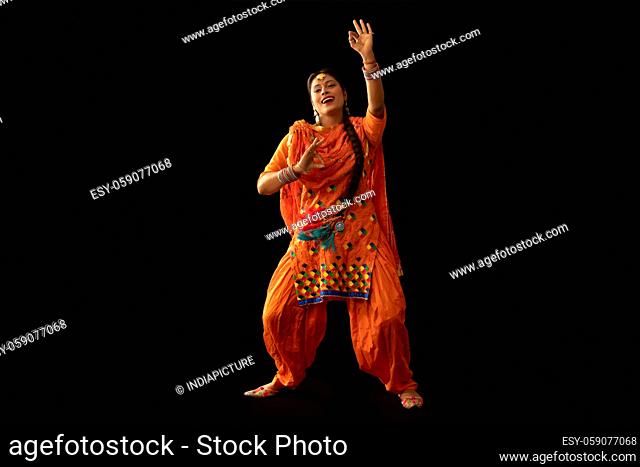 A woman in Giddha costume depicting a dance step with hand gestures