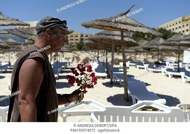 A tourist from Germany, who has been spending his vacations here for over 20 years, lays flowers for the victims on the beach of the Imperial Marhaba Hotel in...