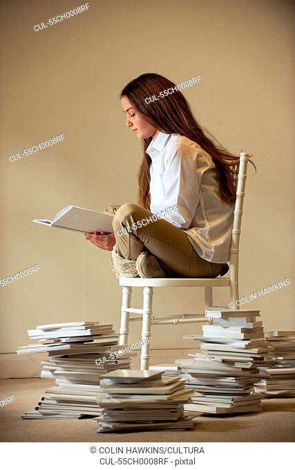 Girl sitting on chair reading book