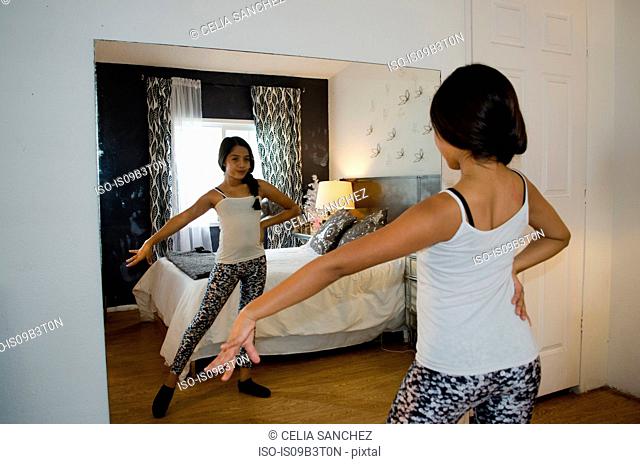 Young girl at home, practising dance moves in front of mirror