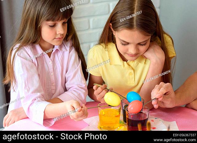 Children stain eggs in a special dye in glasses