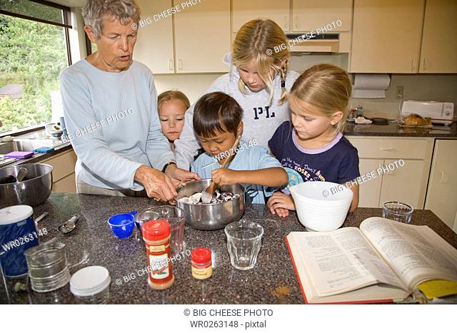 Woman teaching cooking to her grandchildren in the kitchen