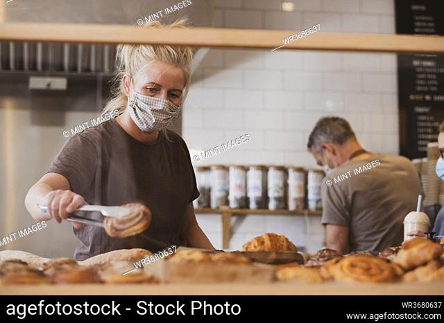 Blond waitress wearing face mask working in a cafe