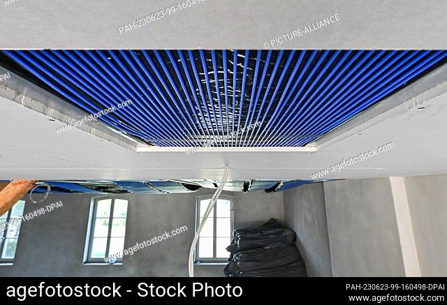 PRODUCTION - 22 June 2023, Brandenburg, Petersdorf: On a construction site in one room of a house, a capillary tube mat is installed on the ceiling as surface...
