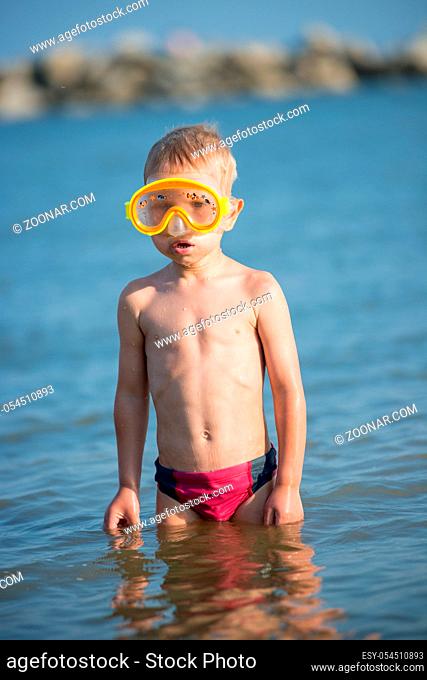 Little boy with snorkel by the sea. Cute little kid wearing mask and flippers for diving at sand tropical beach. Ocean coast