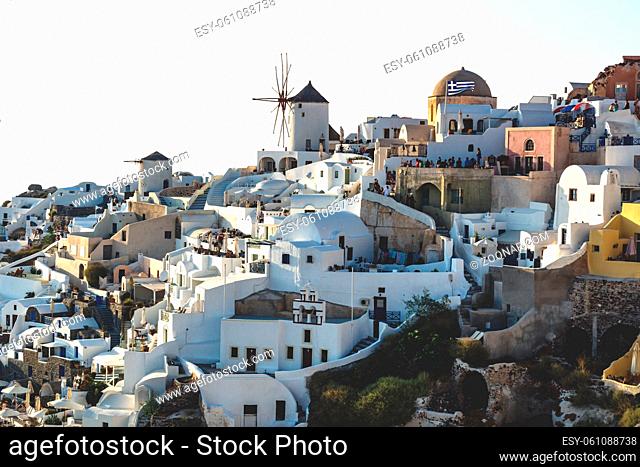 View on Greek village with wind mill on cliffs along the ocean with last sunbeams, Oia, Santorini, Greece