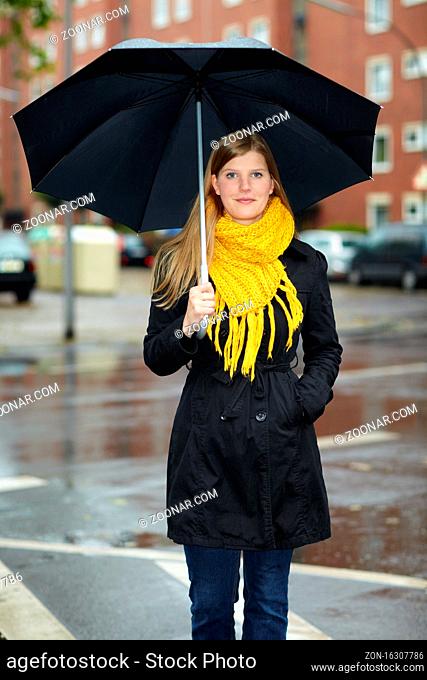 Blonde Frau mit Regenschirm bei Regen