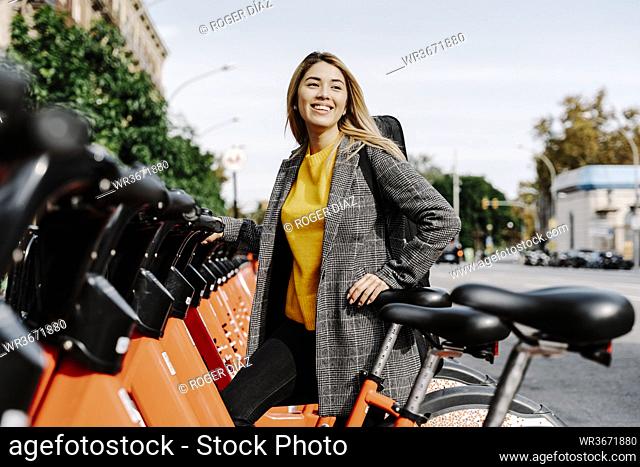 Young woman with violin case renting bicycle in city