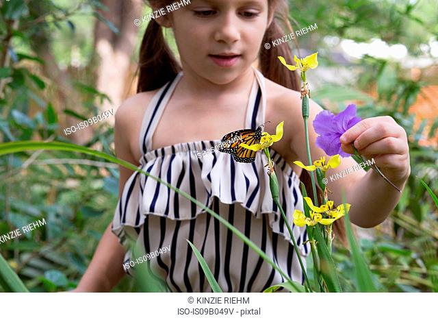 Girl looking at monarch butterfly on flower