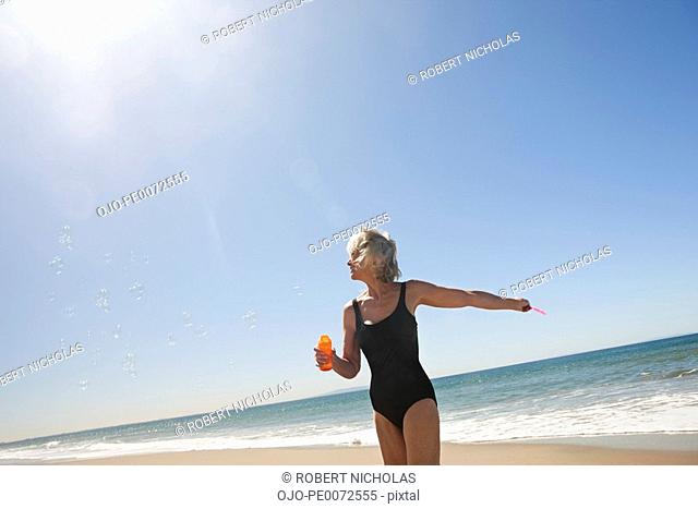 Senior woman blowing bubbles on beach