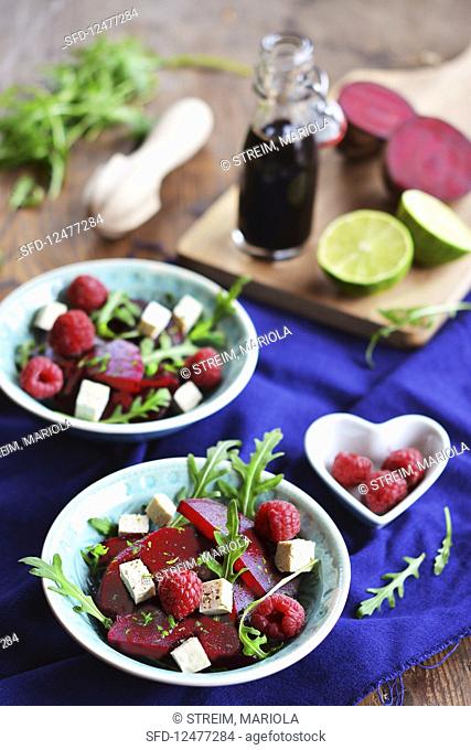 Rocket salad with beetroot, natural tofu and raspberries, with balsamic vinegar and limes in the background
