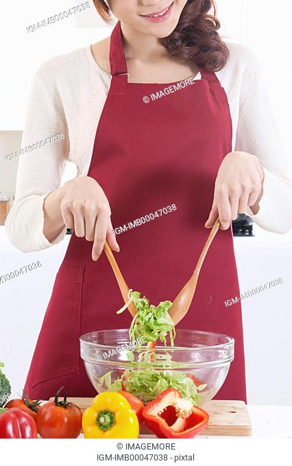 Young woman making salad with smile