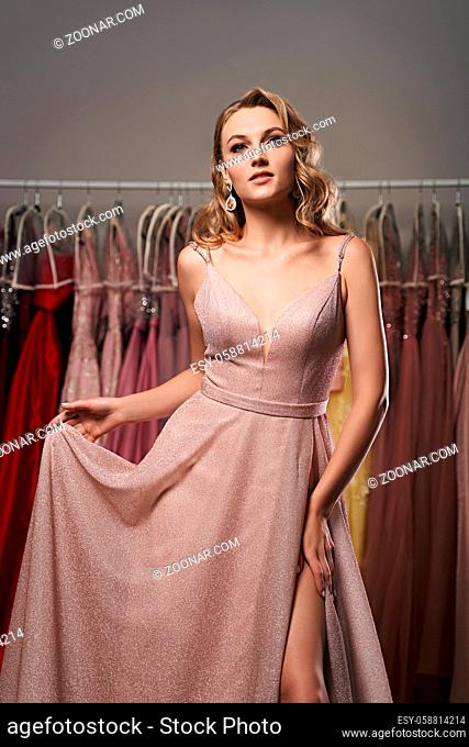 Model selecting an outfit for occasion in dress hire service with many options on background