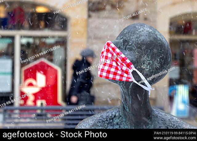 19 January 2021, Thuringia, Ilmenau: A figure in front of a pharmacy wears a mouth-nose protection. With an authorization slip