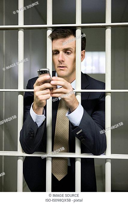 Businessman in cell with cellphone