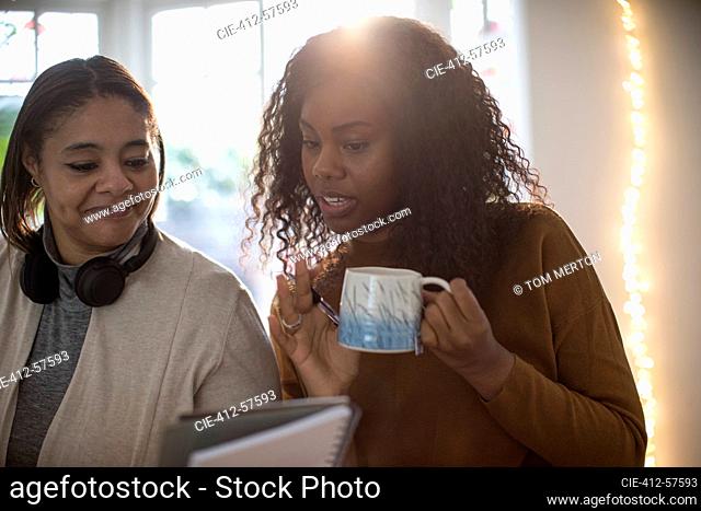 Madre e hija bebiendo té y usando tableta digital