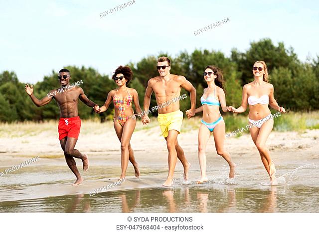 happy friends running on summer beach