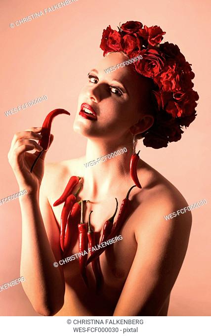 Portrait of pin-up girl wearing red flowers and decorated with red peppers