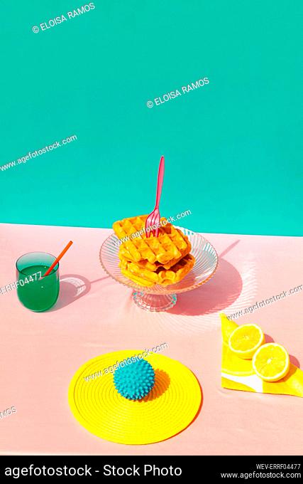 Studio shot of waffle, juice, lime and rubber ball kept on table