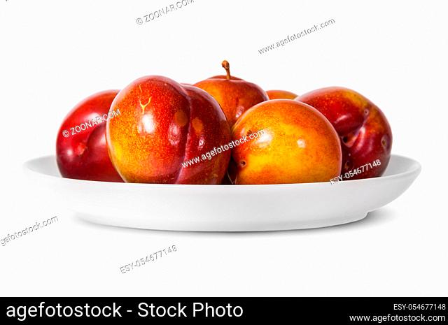 In front red and yellow plums on white plate isolated on white background