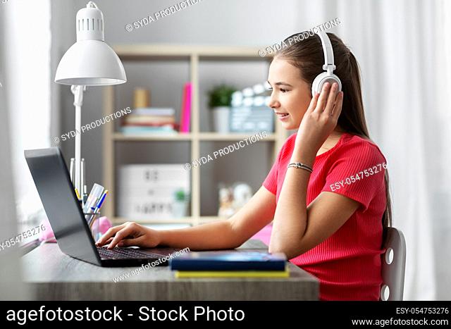 girl in headphones with laptop computer at home