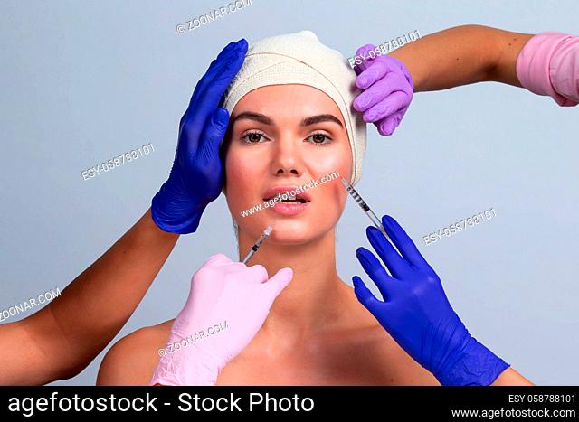 Attractive young woman gets cosmetic injection. Doctors hands making an injection in face. Beauty Treatment