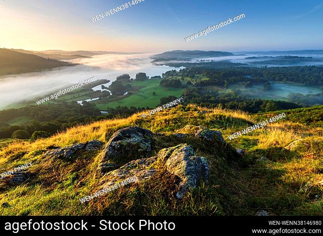 Sunrise at Lake Windermere with early morning mist and fog sweeping over the landscape. Photographed from Loughrigg Fell, above Clappersgate, near Ambleside