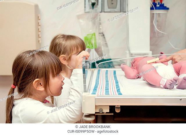 Two sisters looking at newborn baby sister