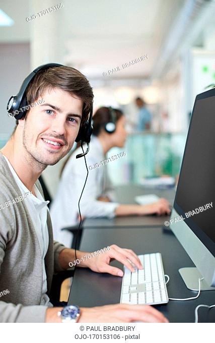 Businessman with headphones working at computer in office