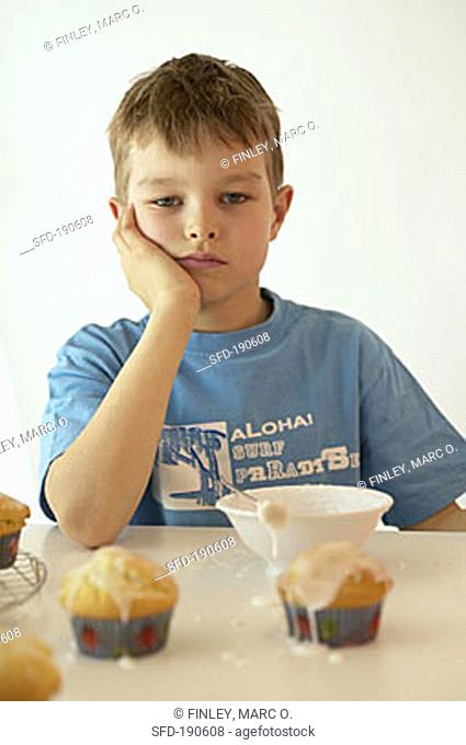 Boy with glacé icing and iced muffins
