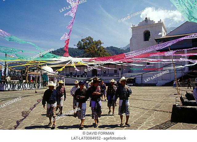 Santiago village. Men in square under coloureds streamers. Traditional male dress. Hats, long shorts