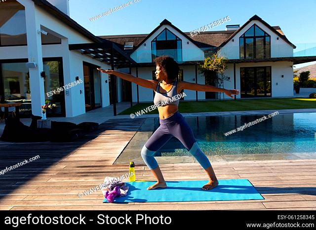 African american young woman practicing yoga outdoors near the pool