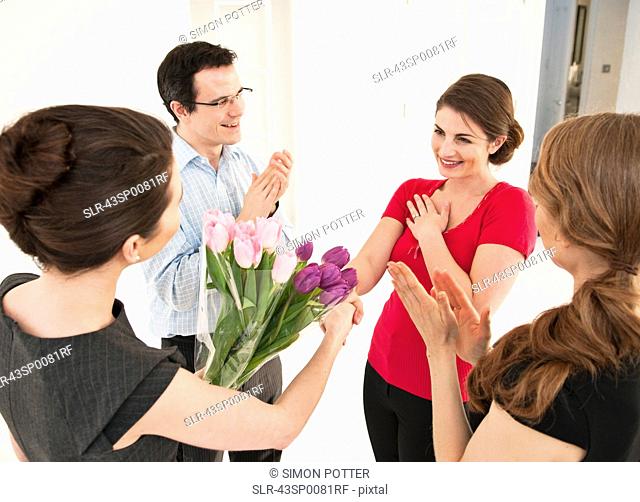 Business people giving colleague flowers
