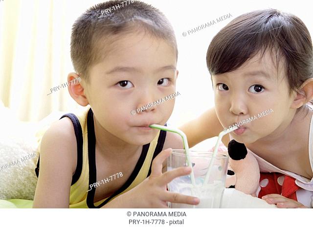 Close-up of a boy and girl drinking milk