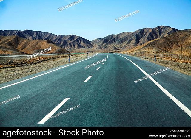Long empty asphalt road in desert with clear blue sky