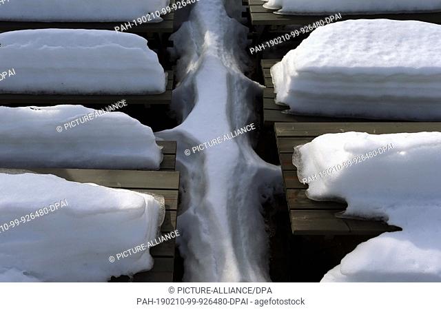 10 February 2019, Bavaria, Aitrang: Snow mountains melt in the sunshine on the benches and tables of an excursion restaurant on Lake Elbe
