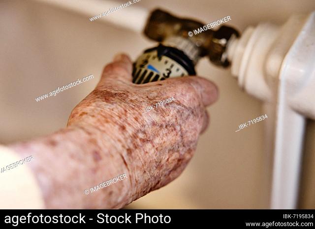 Hand of a senior citizen with age spots on the thermostat of a heater, Cologne, North Rhine-Westphalia, Germany, Europe