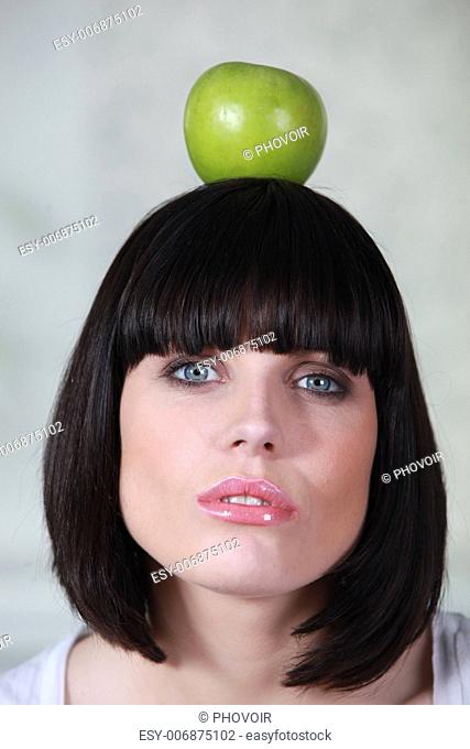 a woman holding an apple on her head
