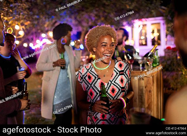 Happy woman drinking and talking with friend at garden party