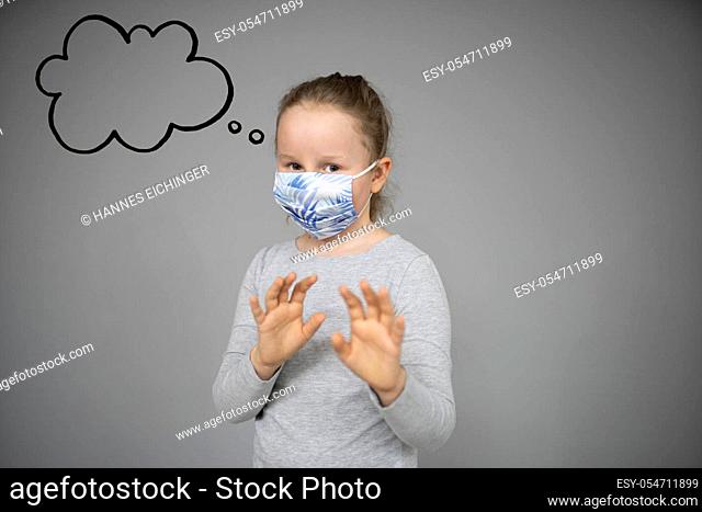 girl trying to stay healthy by wearing a mask to protect him against corona virus covid-19 while looking at copyspace with thought bubble