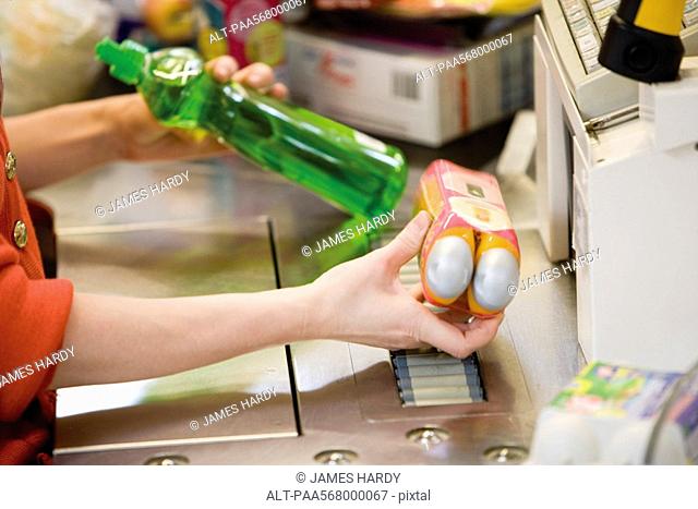 Cashier scanning items at checkout counter, cropped