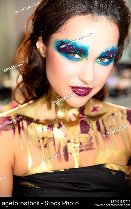 Young alluring brunette with creative make up and body painting
