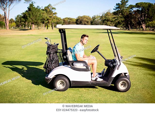 Side view of young man sitting in golf buggy