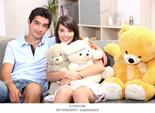 Couple sat on couch with cuddly toys