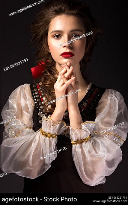 Beautiful Russian girl in national dress with a braid hairstyle and red lips. Beauty face. Picture taken in the studio on a black background