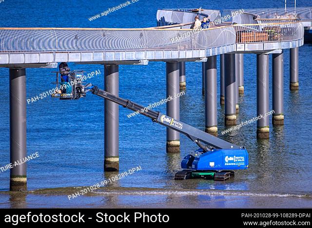 22 October 2020, Mecklenburg-Western Pomerania, Koserow: Construction workers are working from an elevating platform on the new pier on the beach of the island...