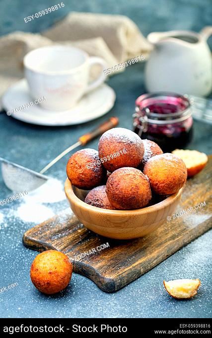 Traditional cottage cheese donuts in a bowl on a wooden serving board, selective focus