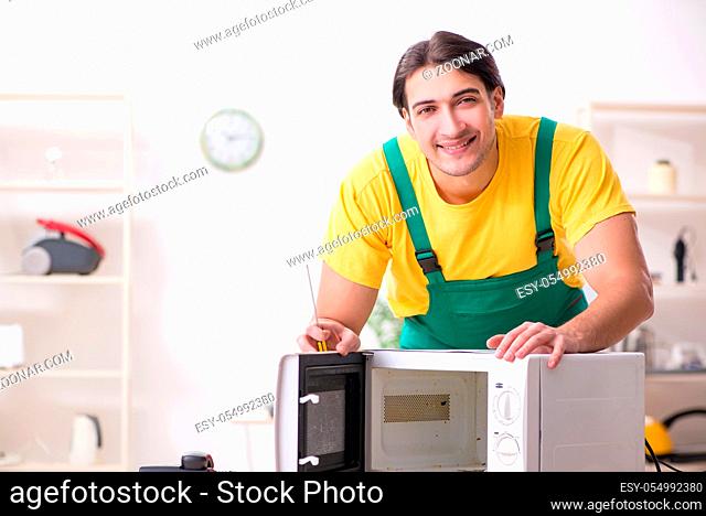 Young repairman repairing microwave in service centre