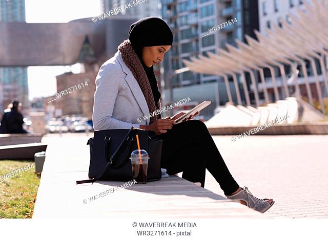 Woman using digital tablet in city